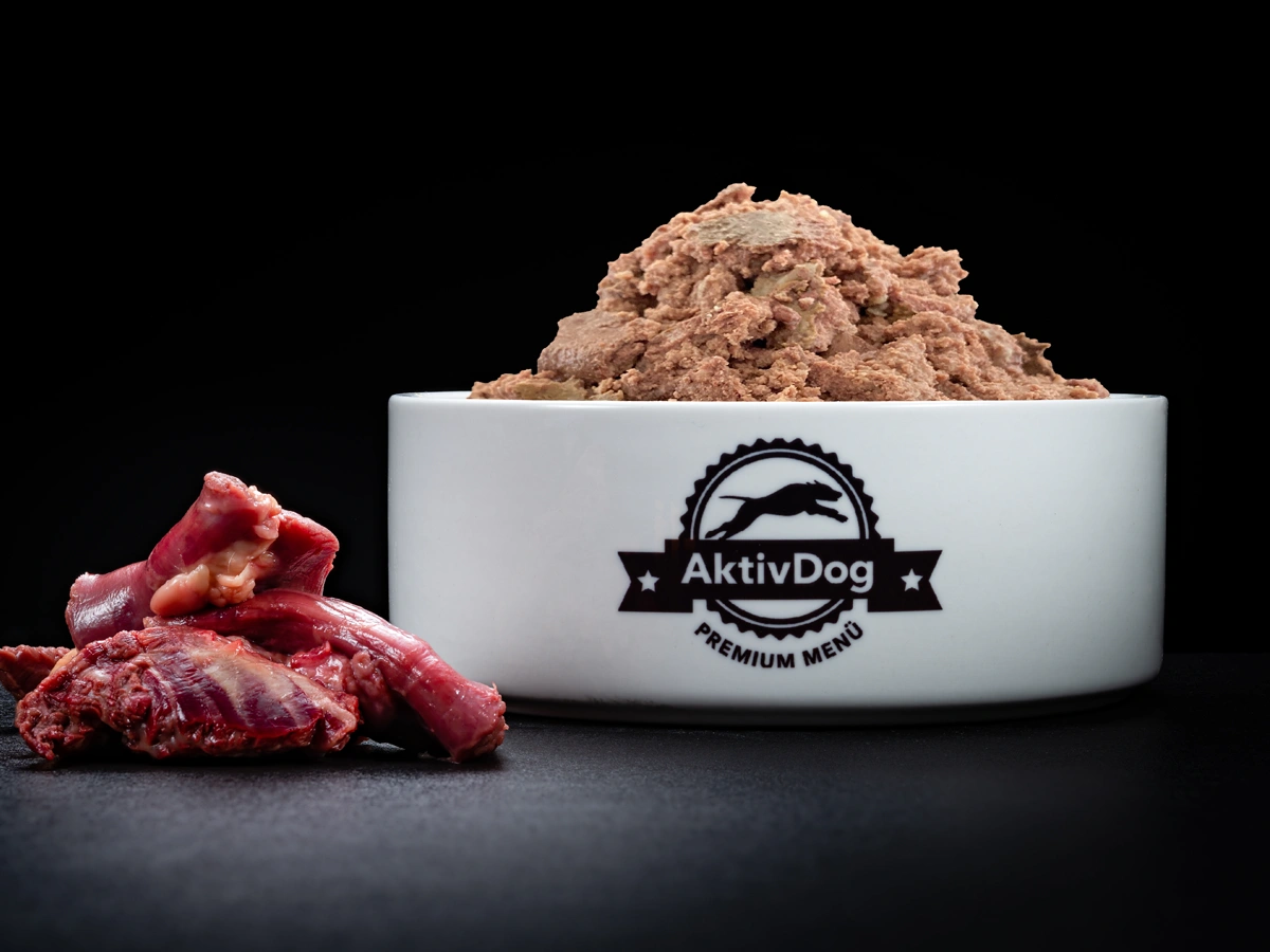 Großaufnahme von AktivDog Hundefutter 100% Pferd mit links daneben liegendem rohen Schweizer Pferdefleisch