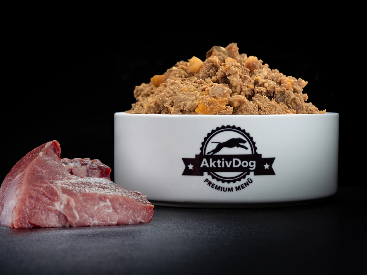 Großaufnahme von AktivDog Hundefutter Ziege mit links daneben liegendem rohen Schweizer Ziegenfleisch