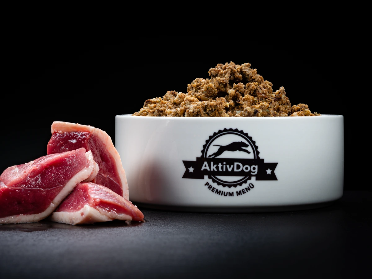 Großaufnahme von AktivDog Hundefutter Ente mit links daneben liegendem rohen Schweizer Entenfleisch
